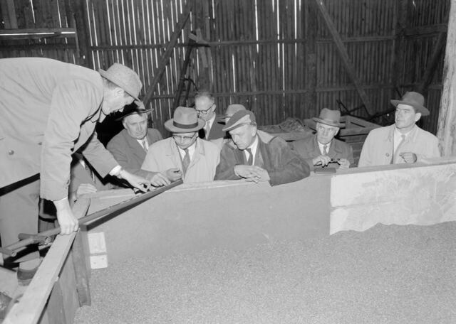Zwart-witfoto van mannen bij een graandroger